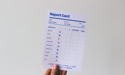 Report card in front of white background with mostly good grades and one bad grade